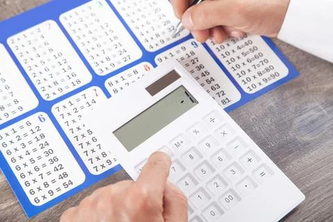 Man using calculator with a multiplication table. Stock Photos