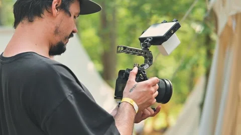 A man is using a camera in an outdoor setting while preparing for a shot. He Stock Footage 345035981