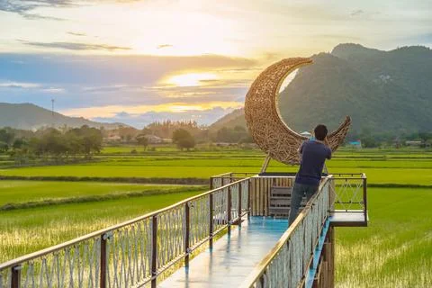 Man using camera to take photo with crescent moon chair made of rattan in p.. Fotos Stock
