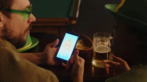 Man Using Car Sharing App on Phone While Hanging out in Pub on March 17 Stock Footage 290451650