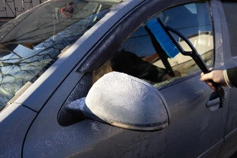 Man using Car Snow Brush to remove snow from the car windshield. Stock Photos