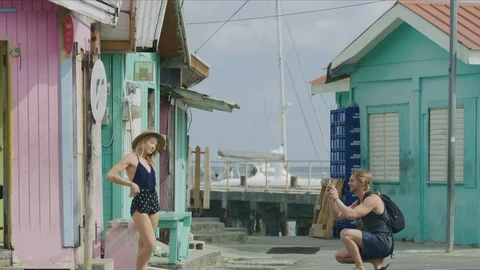 Man using cell phone photographing woman at waterfront / Argyle, Carriacou, Stock Footage 114768197