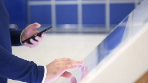 Man is using a cell phone while looking at a large screen Stock Footage 298881382