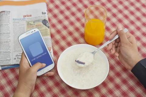 Man using Cell phone while having breakfast Stock Photos