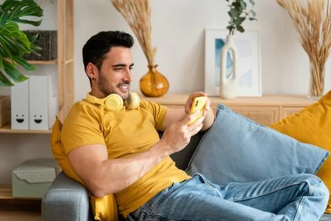 Man using cell phone while relaxing at home. Stock Photos