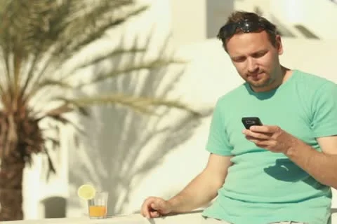 Man using cellphone and drinking exotic cocktail, steadicam shot Stockbeeldmateriaal 10881539