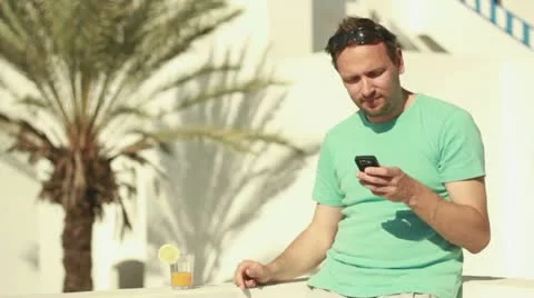 Man using cellphone and drinking exotic cocktail, steadicam shot Stockbeeldmateriaal 10881641