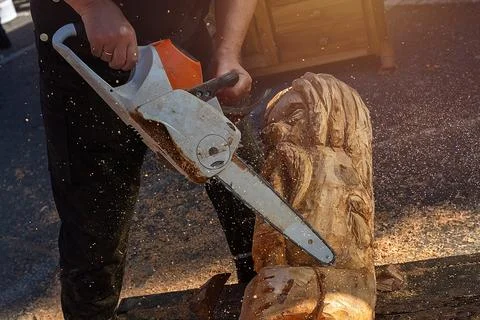 Man using chain saw to create wood carving Stock Photos