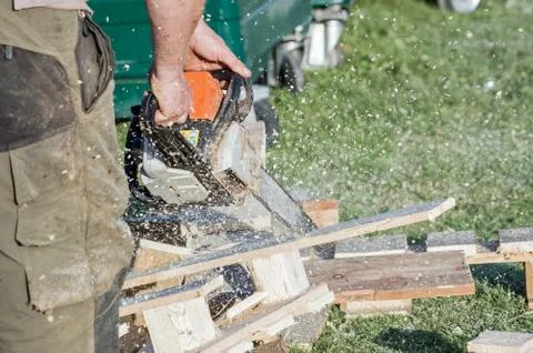 Man using a chainsaw to cut pallets Stock Photos