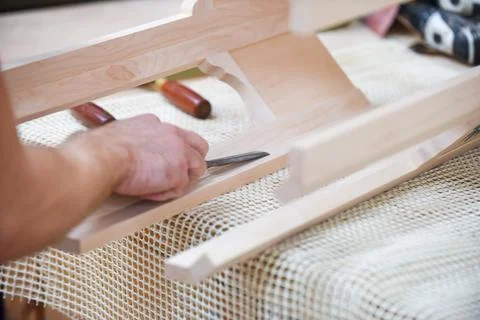 Man is using a chisel to shape and carve wood in carpentry Stock Photos