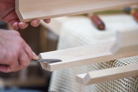 Man is using a chisel to shape and carve wood in carpentry Stock Photos