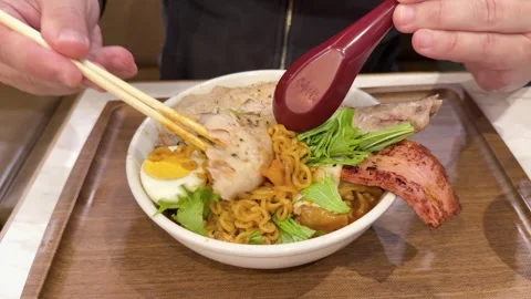 A man using chopsticks to mix and eat a bowl of delicious instant ramen noo.. Vídeos de archivo 333241385