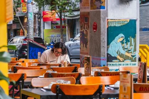 Man Using Chopsticks at a Sidewalk Cafe with Vintage Art Fotos de archivo