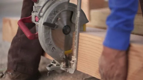 Man using a Circular saw to cut between a big block of wood Stock Footage 137971984