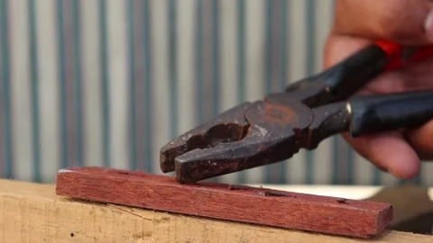A man using a claw hammer pulls out nails from boards. Stock Footage 144091333