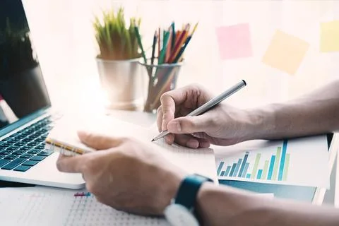 Man using computer and calculator during note some data on notepad for calculate Foto stock