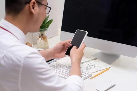 Man using computer and smart phone at the table in office against the window Stock Photos