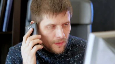 Man using computer and talking on cell phone. Video stock 73988574