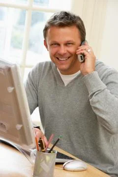 Man Using Computer And Talking On Phone 스톡 사진