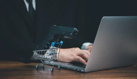 Man using computer buying handgun from online internet seller shop. Stock Photos