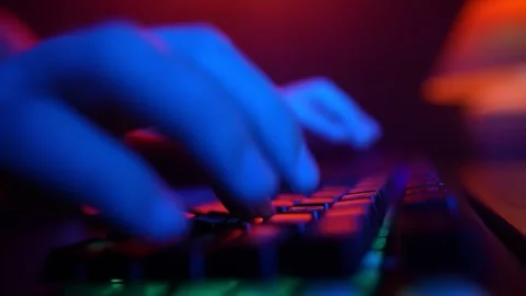 Man Using Computer Keyboard Code Website in Neon Lighting. Hacker and Cybercrime Stock Footage 253220379