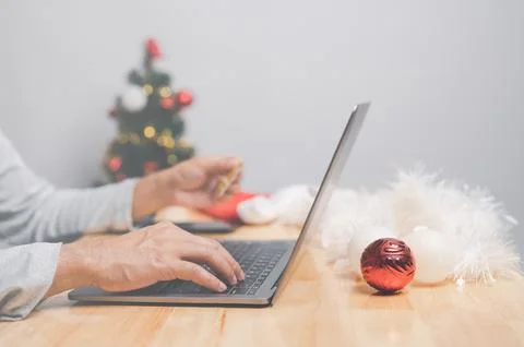 Man using computer laptop indoors to pay for goods of Christmas holiday. Ma.. Stock Photos