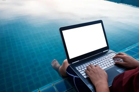 A man using computer laptop, at poolside with dipping legs in the water Stock Photos