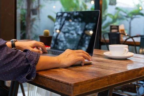 Man using computer mouse working on laptop at table in cafe. Stock Photos