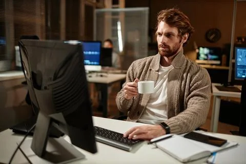 Man using computer in office and drinking coffee Foto stock