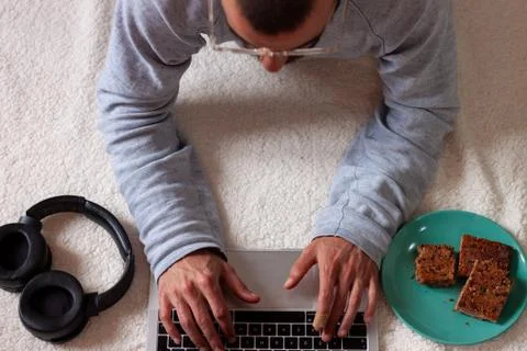 Man using computer while resting on the floor against white background Stock Photos