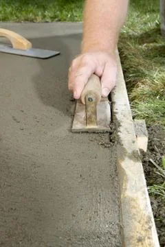 Man using concrete edging tool on wet cement slab Foto stock