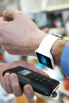Man Using Contactless Payment App On Smart Watch In Store Stock Photos