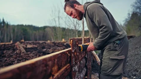 Man Using A Cordless Power Tool To Cut Stacked Wooden Planks Vídeo Stock 346792612