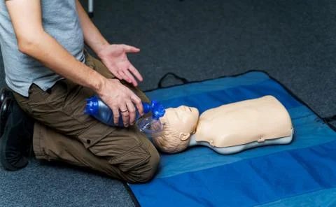 Man using CPR technique on dummy in first aid class. Oxigen mask on medical d Stockfoto's