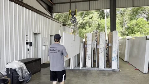 Man using crane to place granite slab next to others Video stock 251402843