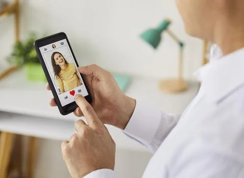 Man using dating app on smartphone, tapping heart to like a profile photo at Fotos de archivo
