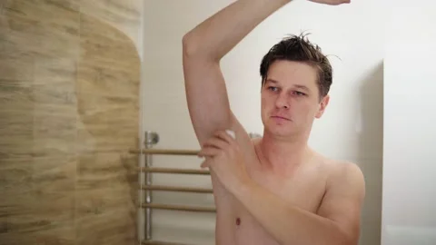 Man using deodorant under his arms in the bathroom Stock Footage 144541818