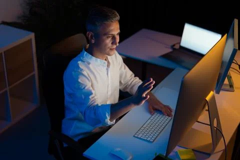 Man Using Desktop Computer in Dimly Lit Modern Office Stock Photos