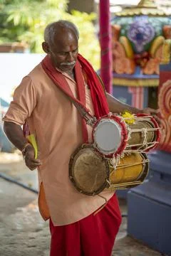 A man using dholak drums in the temple during morning pooja ritual Stock Photos
