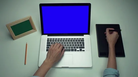 Man using digital graphic tab and laptop with green screen at white desk Video stock 82894255