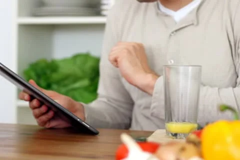 Man using digital tablet and drinking orange juice NTSC Stock Footage 8990519