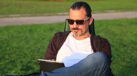 Man using digital tablet in city park Stock Footage 60883673