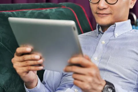 Man using a digital tablet on a couch Stock Photos
