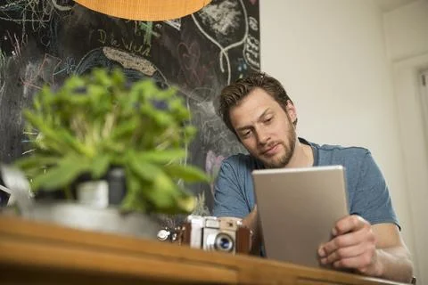 Man using digital tablet in dining room, Munich, Bavaria, Germany Stock Photos