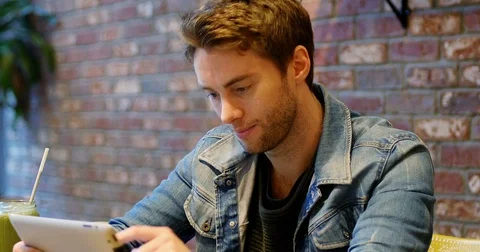 Man using digital tablet with glass of juice on table Stock Footage
