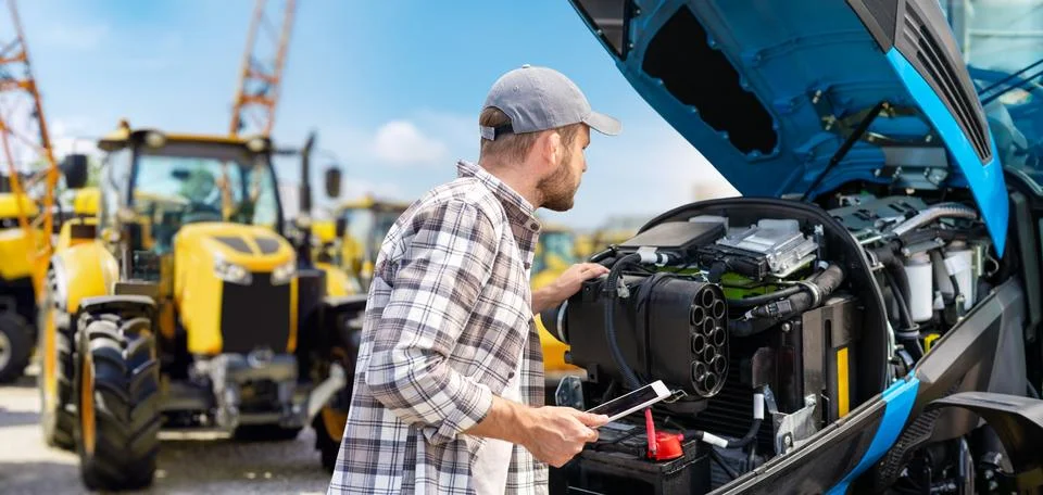 Man using digital tablet to inspect tractor engine with modern modern technol Stock Photos