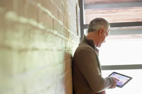 Man using a digital tablet near a window Stock Photos