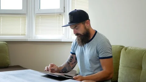 Man using digital tablet on sofa at home. Portrait of a serious man wearing Video stock 98883461