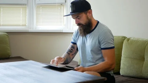 Man using digital tablet on sofa at home. Portrait of a serious man wearing Video stock 98883478