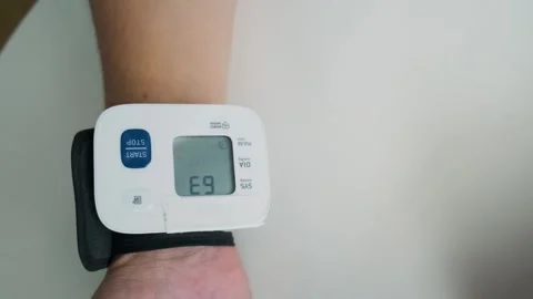 Man using digital wrist blood pressure monitor for measuring blood pressure and Stock Footage 315859812